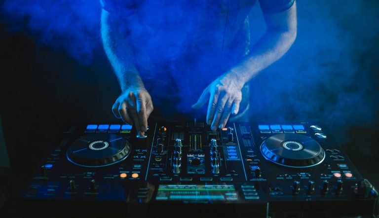 Un DJ travaillant sur une table de mixage sous une lumière bleue